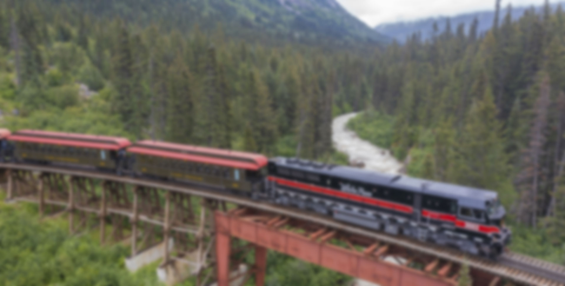 Alaska Train Excursion showing a train crossing a bridge with a wild roaring river underneath it